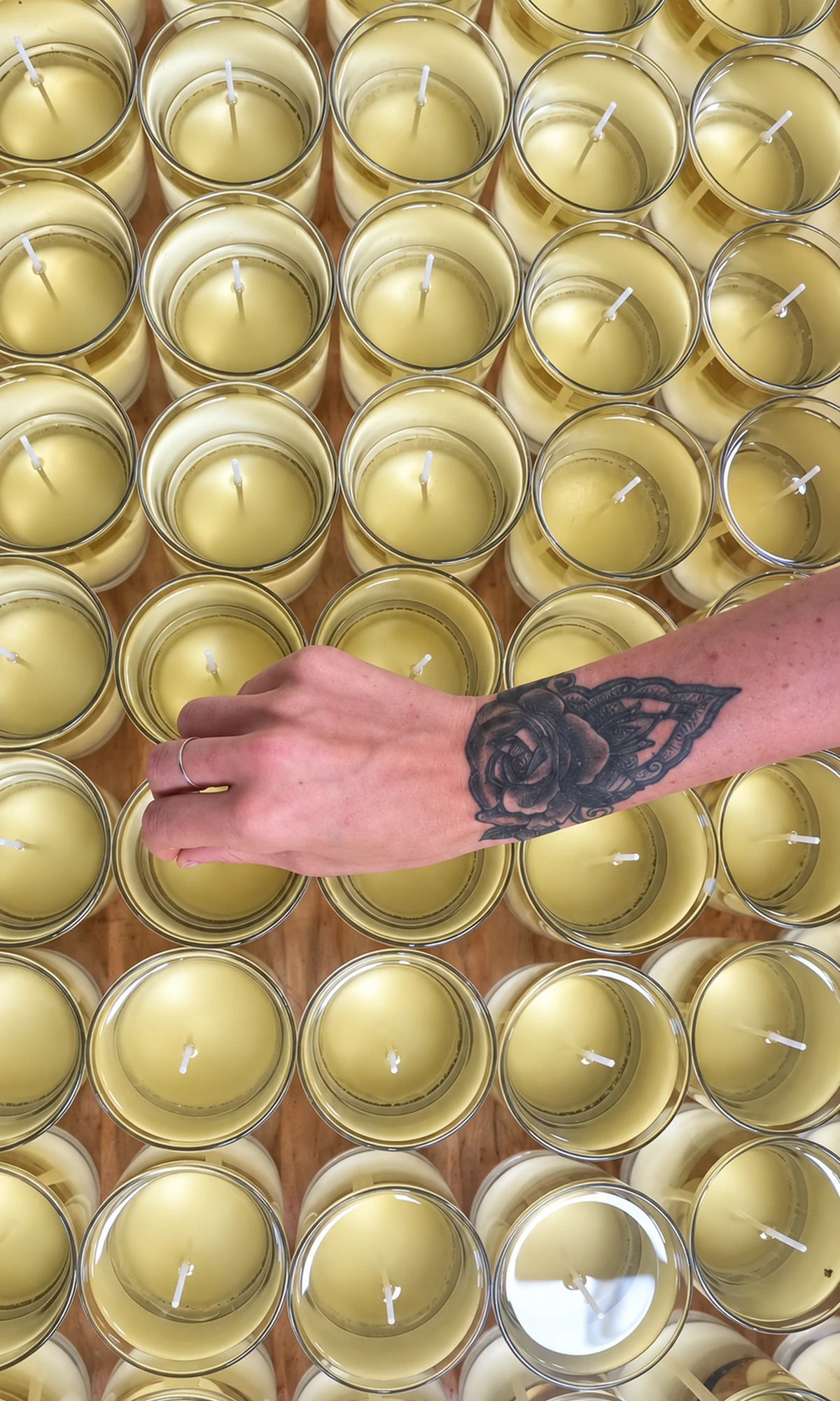 Geste de réglage d’une mèche parmi des bougies en cours de fabrication